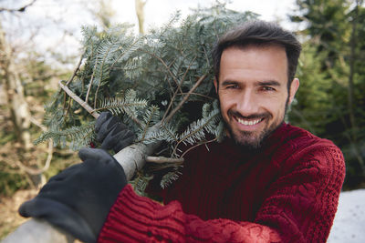 Portrait of smiling man with branch outdoors