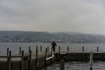 People looking at sea by cityscape against sky