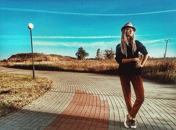 Full length of young woman standing on park bench