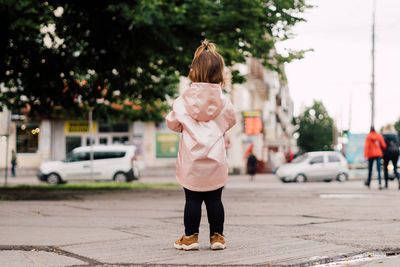 Rear view of girl standing on road