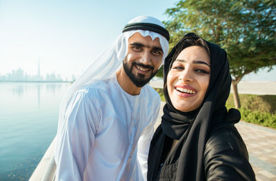 Portrait of smiling couple wearing traditional clothing standing against sky