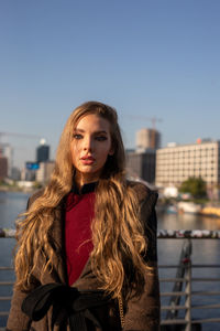 Portrait of young woman standing against sky