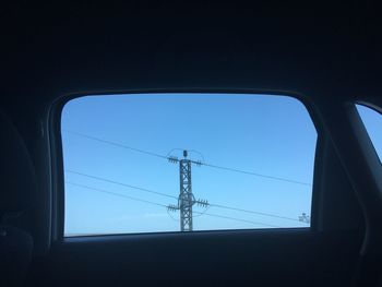 Low angle view of electricity pylon against clear blue sky