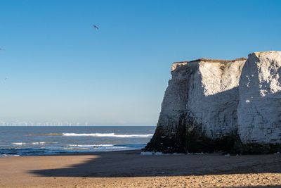 View of bird and limestone cliffs on beach against sky