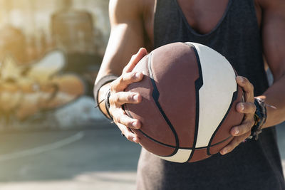 Midsection of man holding basketball