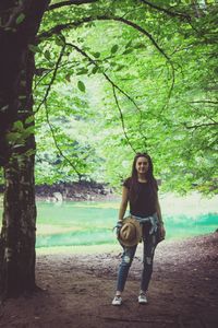 Portrait of young woman standing against trees