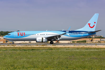 Airplane flying over land against sky