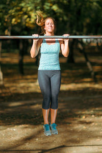 Woman exercising on horizontal bar outdoors in the fall, in public park