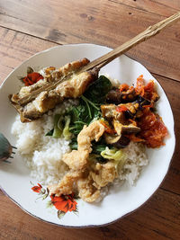 A plate of vegetable rice and side dishes of stingrays and fried sea fish with chili sauce
