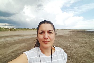 Portrait of woman standing at beach against sky