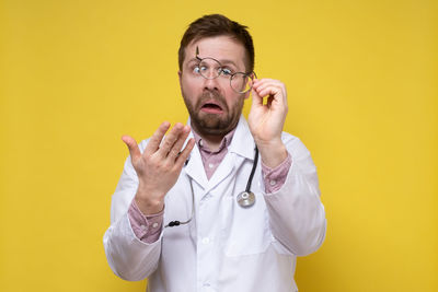 Mid adult man standing against yellow background