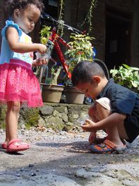 Side view full length of boy crouching by sister