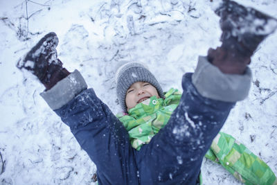 High angle view of boy falling on snow covered land