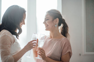 Bridesmaid and bride holding champagne flute