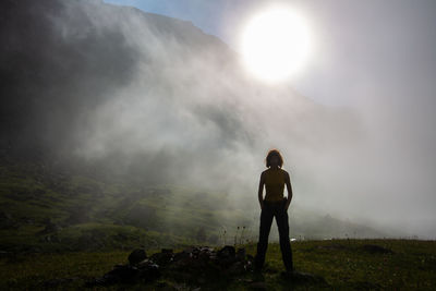 Rear view of man standing on mountain against sky