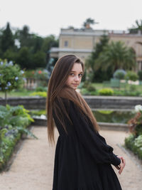 Portrait of young woman standing against building