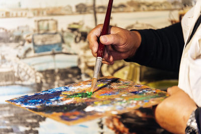 Midsection of man holding cardboard and paintbrush