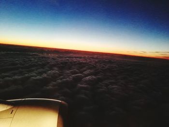 Airplane wing against sky during sunset