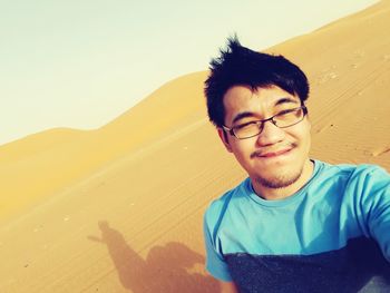 Portrait of smiling boy in desert against sky