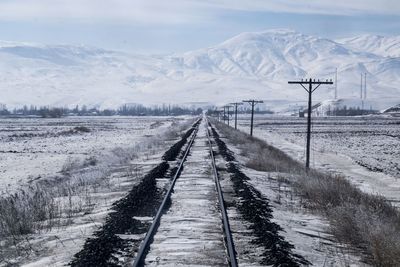 Snow covered road by snowcapped mountain against sky