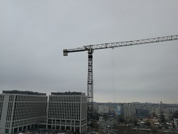 Crane at construction site against sky in city