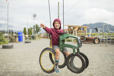 Young boy sits on play ride on tractor at farm made from recycled tire