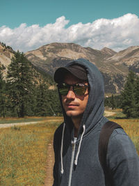 Portrait of young man standing on mountain road against sky