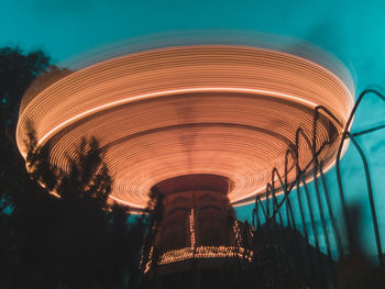 Low angle view of illuminated carousel against sky at night