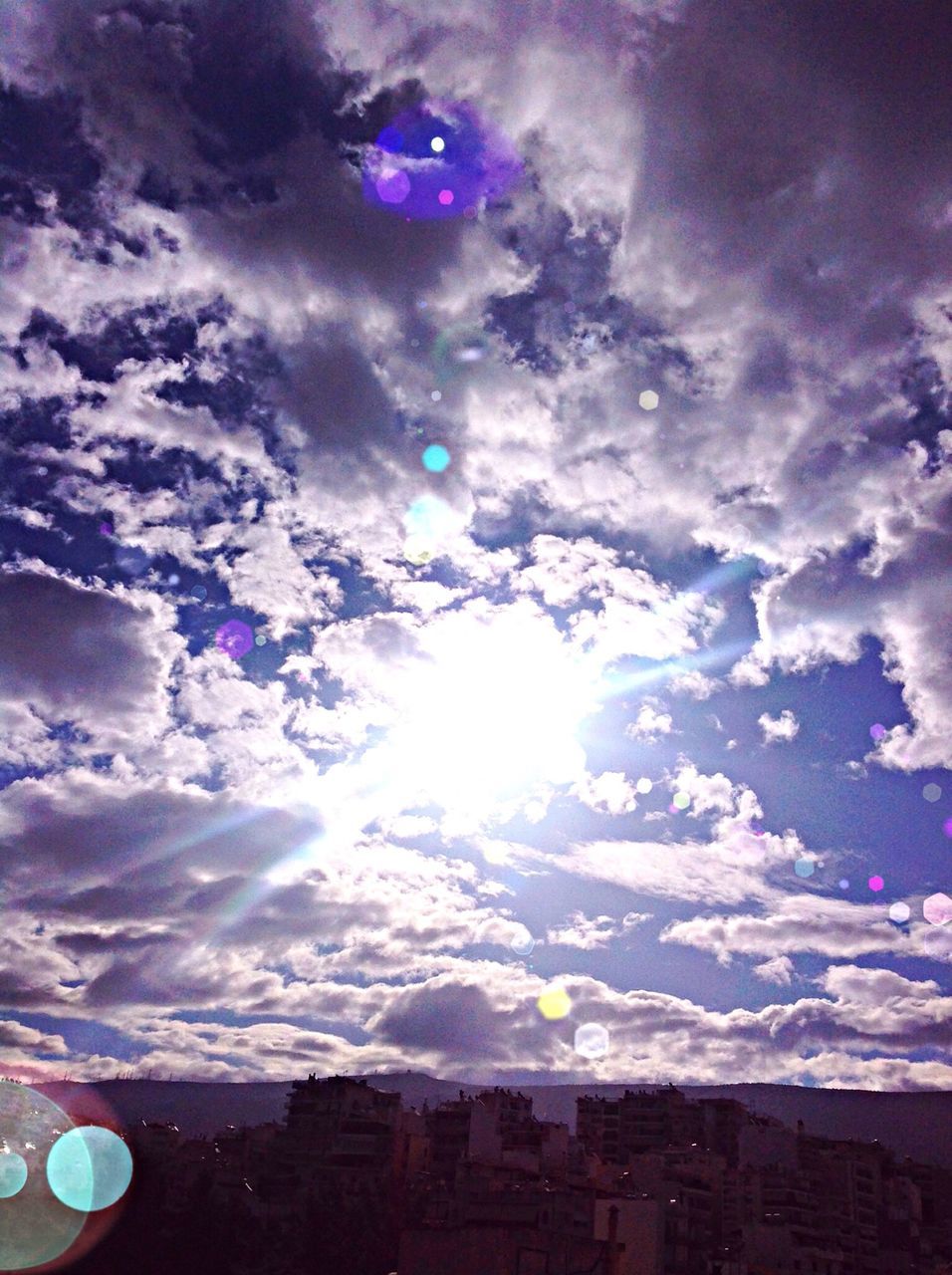sky, cloud - sky, sun, lens flare, beauty in nature, sunbeam, sunlight, nature, weather, scenics, cloudy, tranquility, blue, cloud, tranquil scene, outdoors, no people, low angle view, rainbow, day