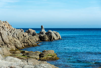 Rock formations on shore against blue sky