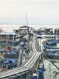 Boats moored at harbor against sky