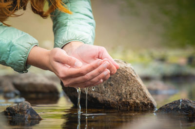 Hands and water. close-up of a woman taking water from a mountain lake in her hands