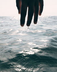 Midsection of person surfing in sea against sky