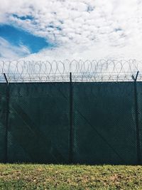 Scenic view of field against sky seen through chainlink fence