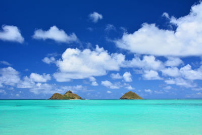 Turquoise waters and blue skies at na mokulua aka mokuluas world famous lanikai beach oahu, hawaii.