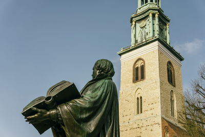 Low angle view of statue against building against sky