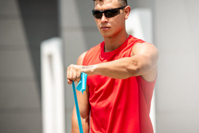 Young man wearing sunglasses standing against wall