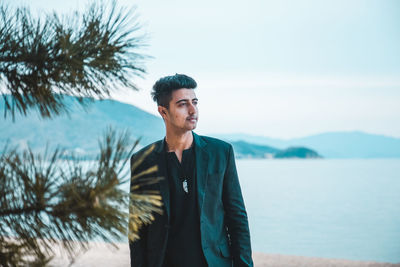 Thoughtful young man standing against sea