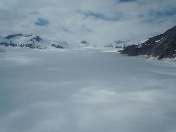 Snow covered mountains against cloudy sky