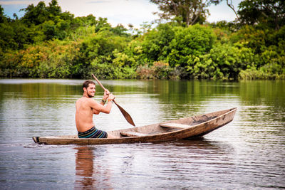 Man in boat on lake against trees