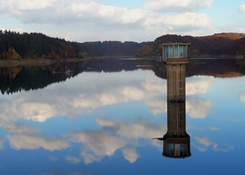 Tower reflection in reservoir against sky