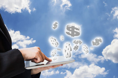 Low angle view of man using mobile phone against sky