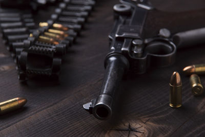 High angle view of handgun and bullets on wooden table