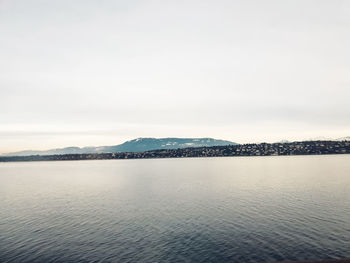 Scenic view of sea by mountain against sky