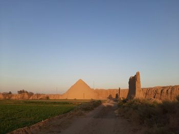 Road amidst desert against clear blue sky