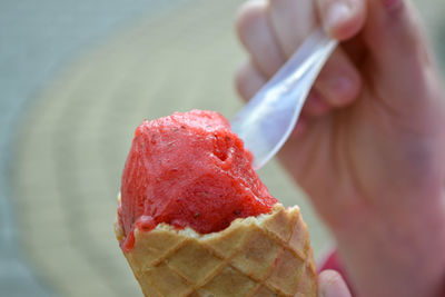 Holding fresh waffle cone with raspberry ice cream