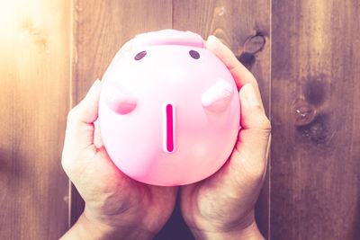 Cropped hands holding piggy bank on table