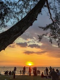 Silhouette people on beach against sky during sunset