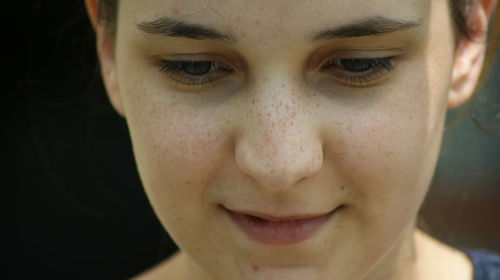 Close-up of thoughtful young woman with freckles