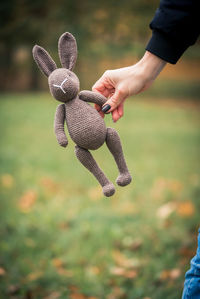 Cropped hand of woman holding stuffed toy outdoors